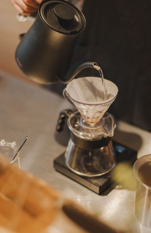 Free Barista pours hot water in Shinjuku cafe, creating perfect espresso with pour-over technique. Stock Photo