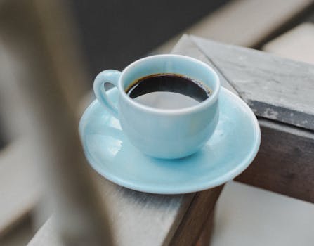A simple, elegant photograph of black coffee in a blue cup on a wooden table, evoking a sense of calm.