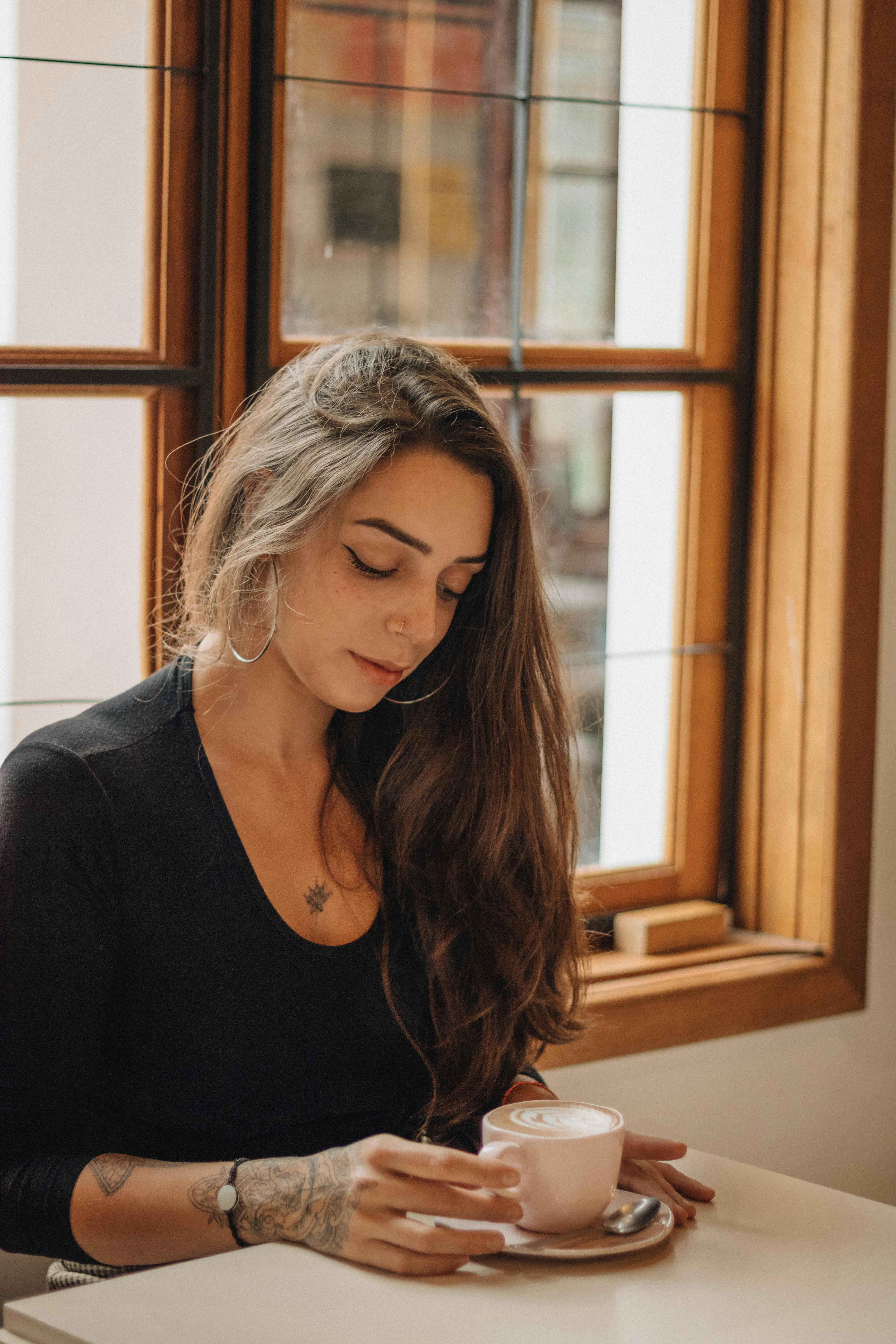 Young woman sipping coffee in a cozy cafe, enjoying a peaceful moment.