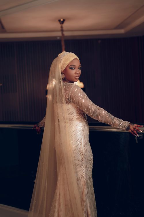 Free A woman in an elegant evening gown and veil poses indoors with a sophisticated ambiance. Stock Photo