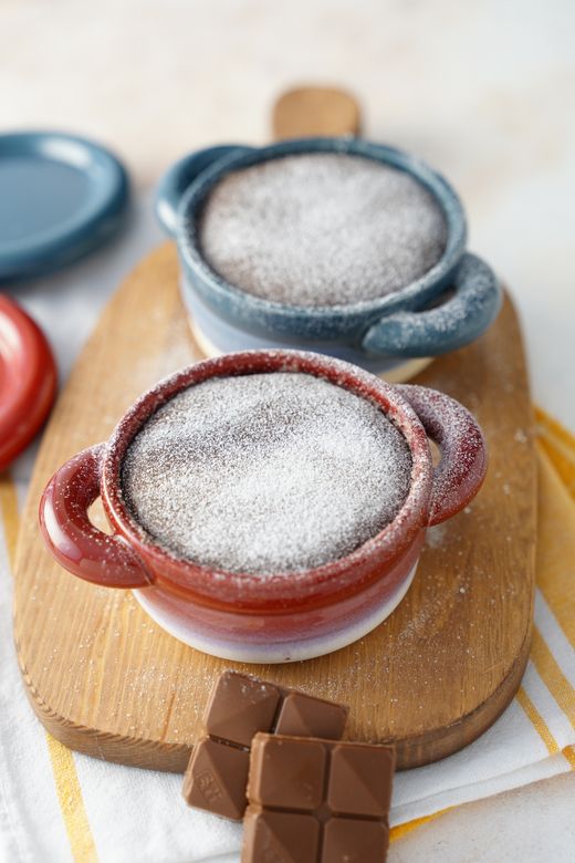 Red and blue mini cocottes dusted with sugar on a wooden board