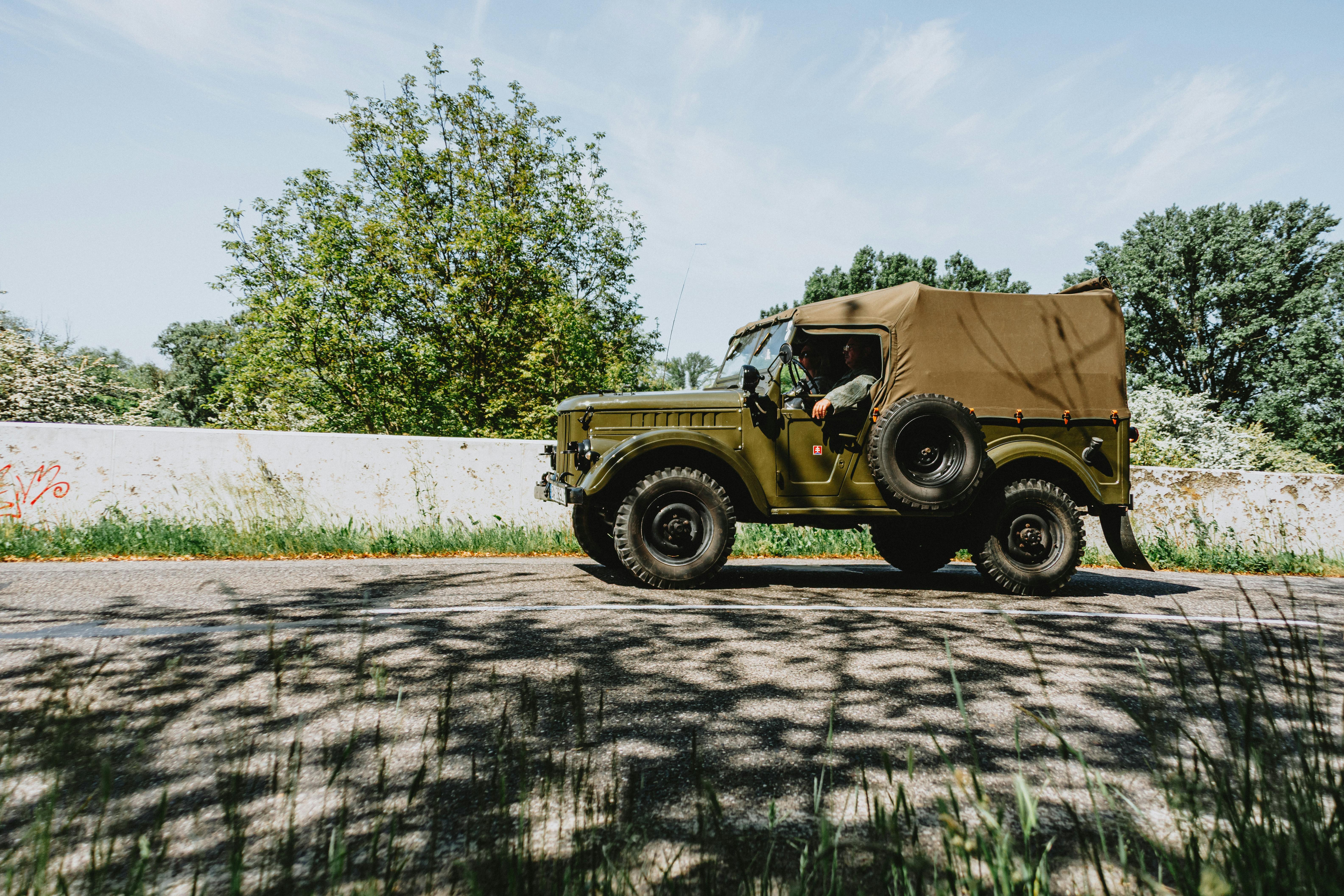 Classic military jeep on a road with clear skies and natural surroundings.