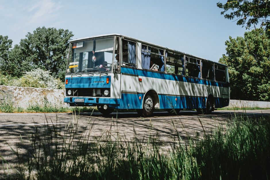 A vintage blue bus parked outdoors on a sunny day surrounded by greenery.