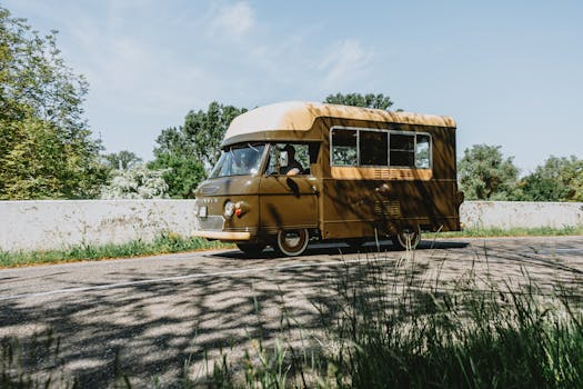 Classic brown camper van on a scenic summer road trip under a clear blue sky.