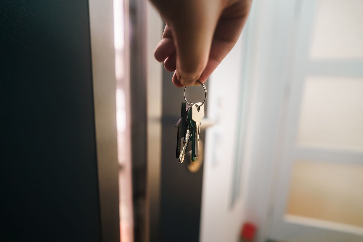 Hand holding keys at the doorway of a new home