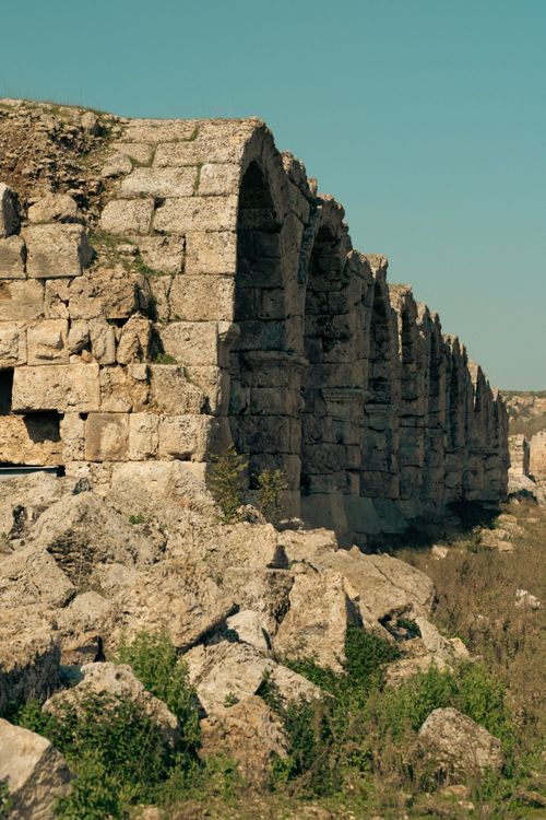 Free Serene view of historic stone aqueduct ruin with arches under clear sky, surrounded by nature. Stock Photo