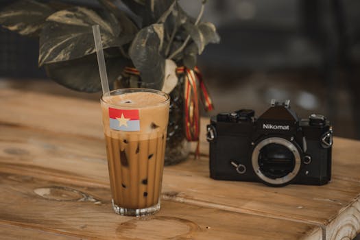 A glass of Vietnamese iced coffee next to a vintage camera on a rustic wooden table.