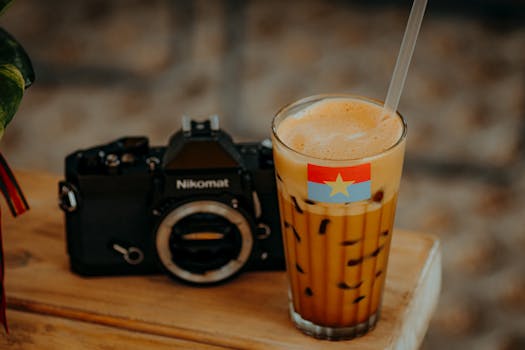 Vintage camera with a refreshing Vietnamese iced coffee on a wooden table.