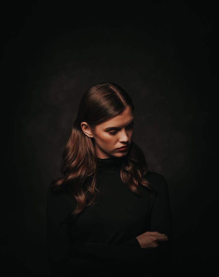 Photo Of Woman In Black Turtleneck Sweater Posing In Front Of Black Background While Looking Away