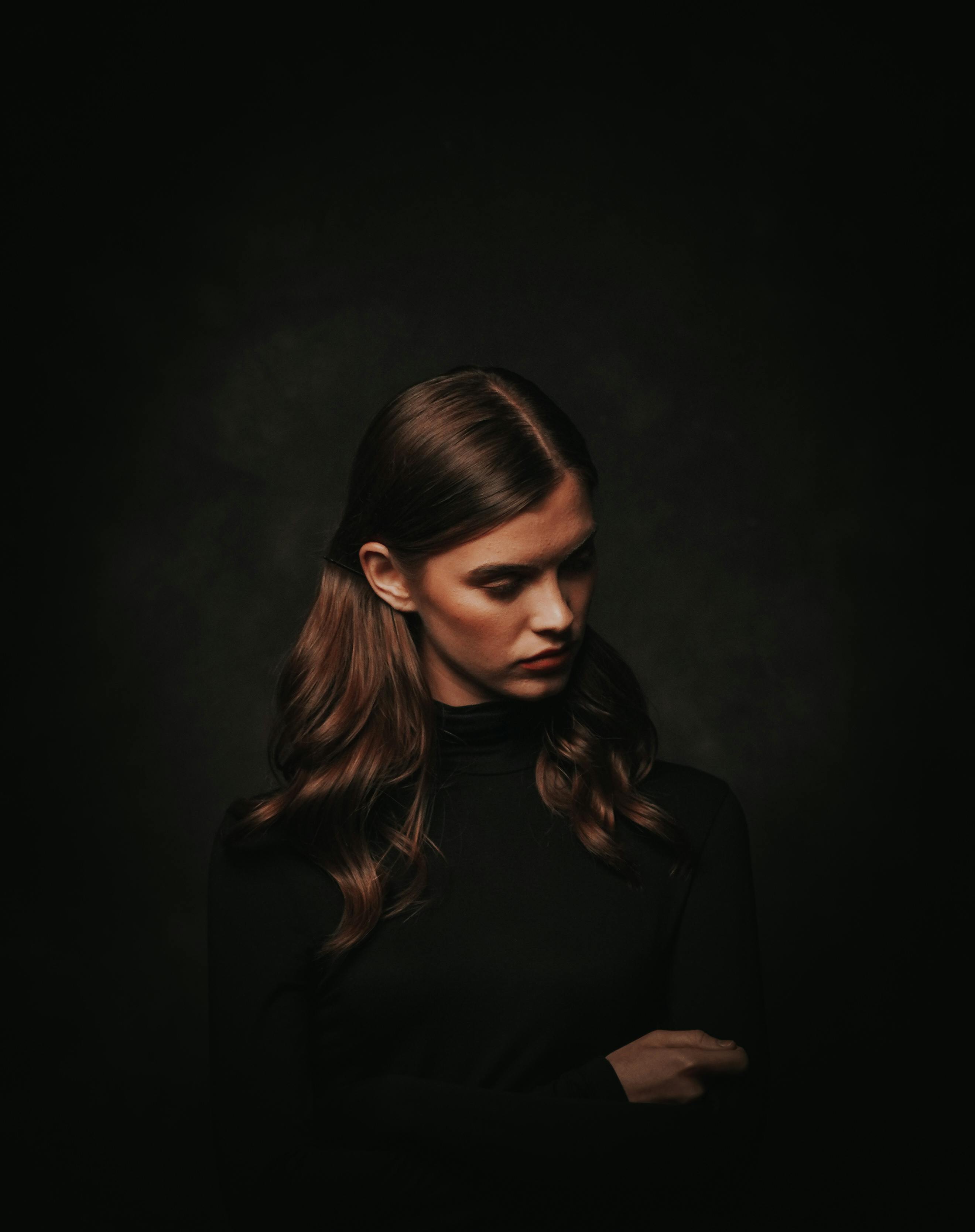 Photo of Woman in Black Turtleneck Sweater Posing In Front of Black  Background While Looking Away · Free Stock Photo