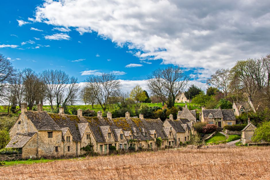 Picturesque Cotswold village with historic stone houses and vibrant spring scenery.