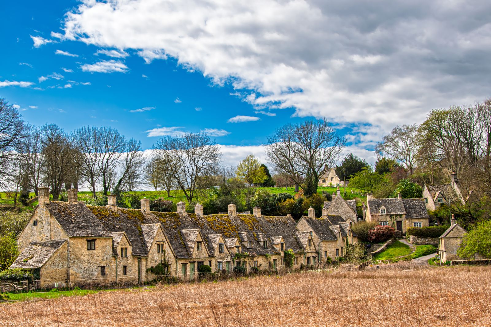 A row of honey-colored stone cottages in a classic Cotswolds village