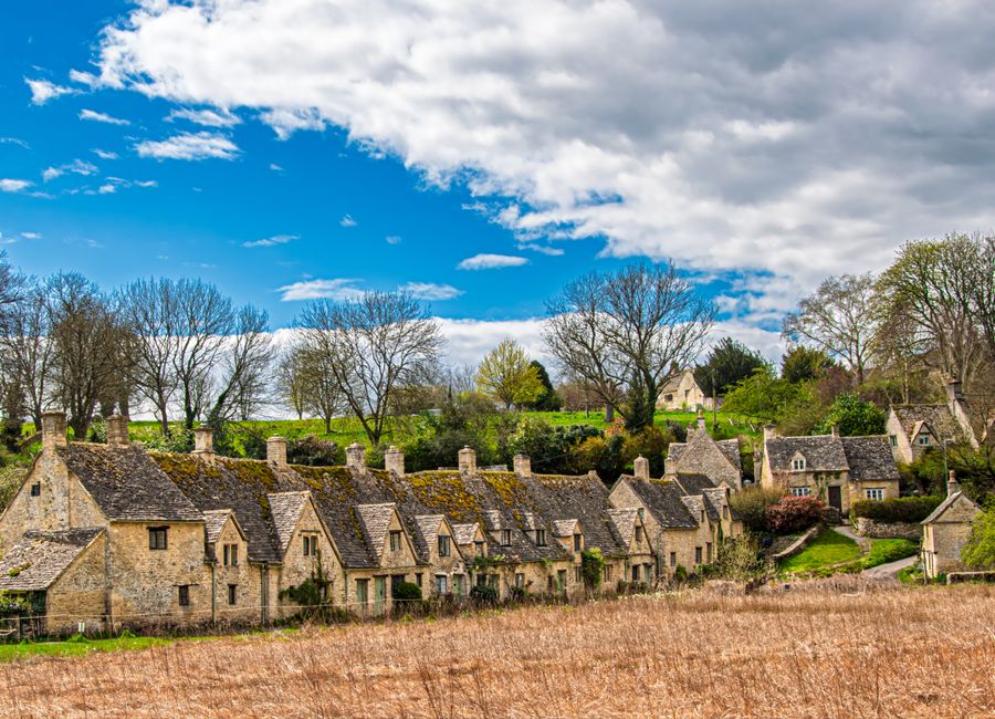 Picturesque Cotswold village with historic stone houses and vibrant spring scenery.