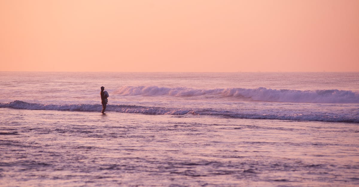 Person Standing on Seashore during Golden Hour