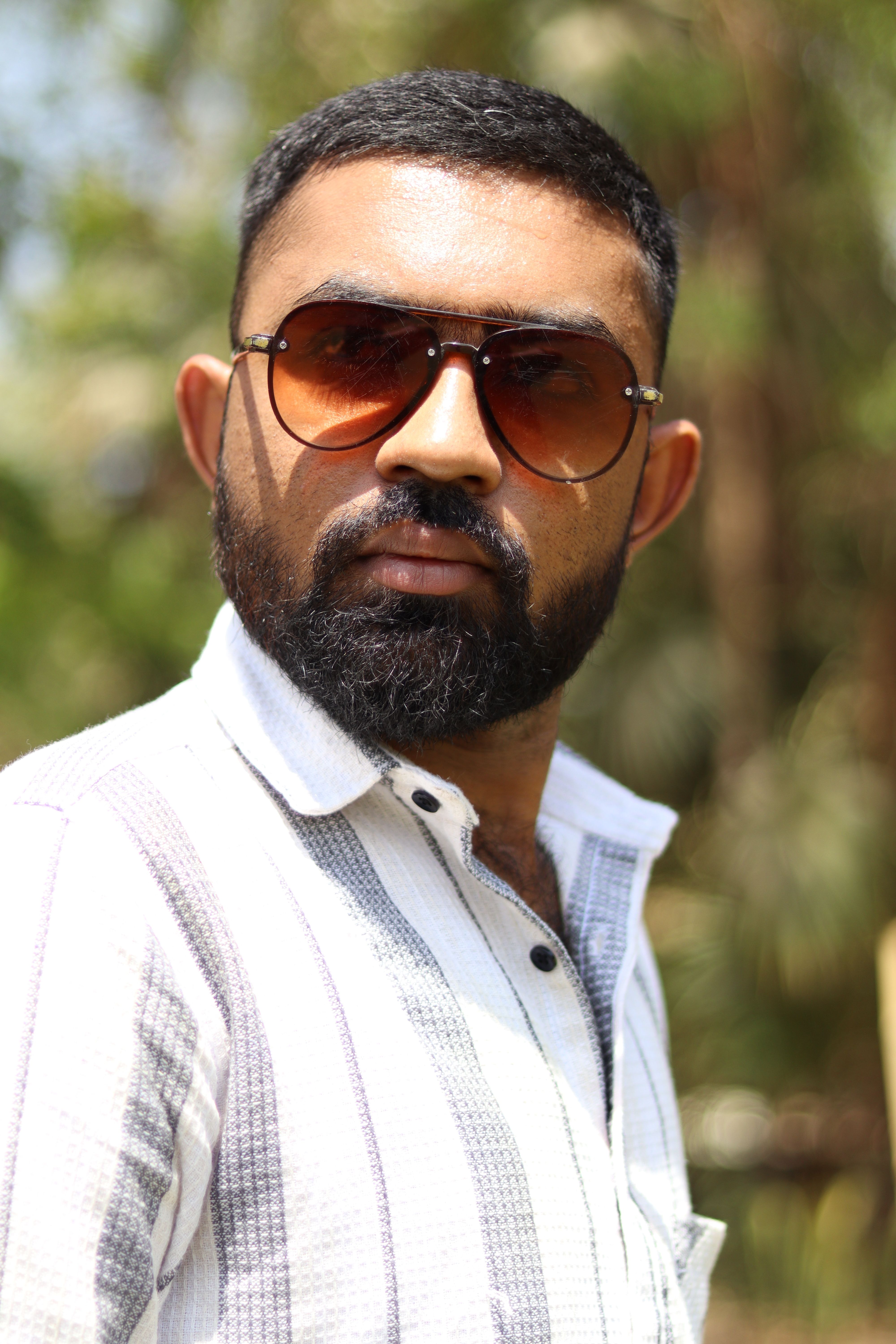 Portrait of a fashionable man wearing sunglasses, outdoors in an Ahmedabad park, Gujarat, India.