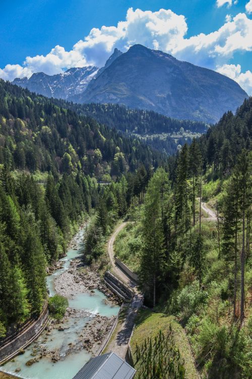 Free Breathtaking alpine view with river, forest, and mountain under a bright sky. Stock Photo