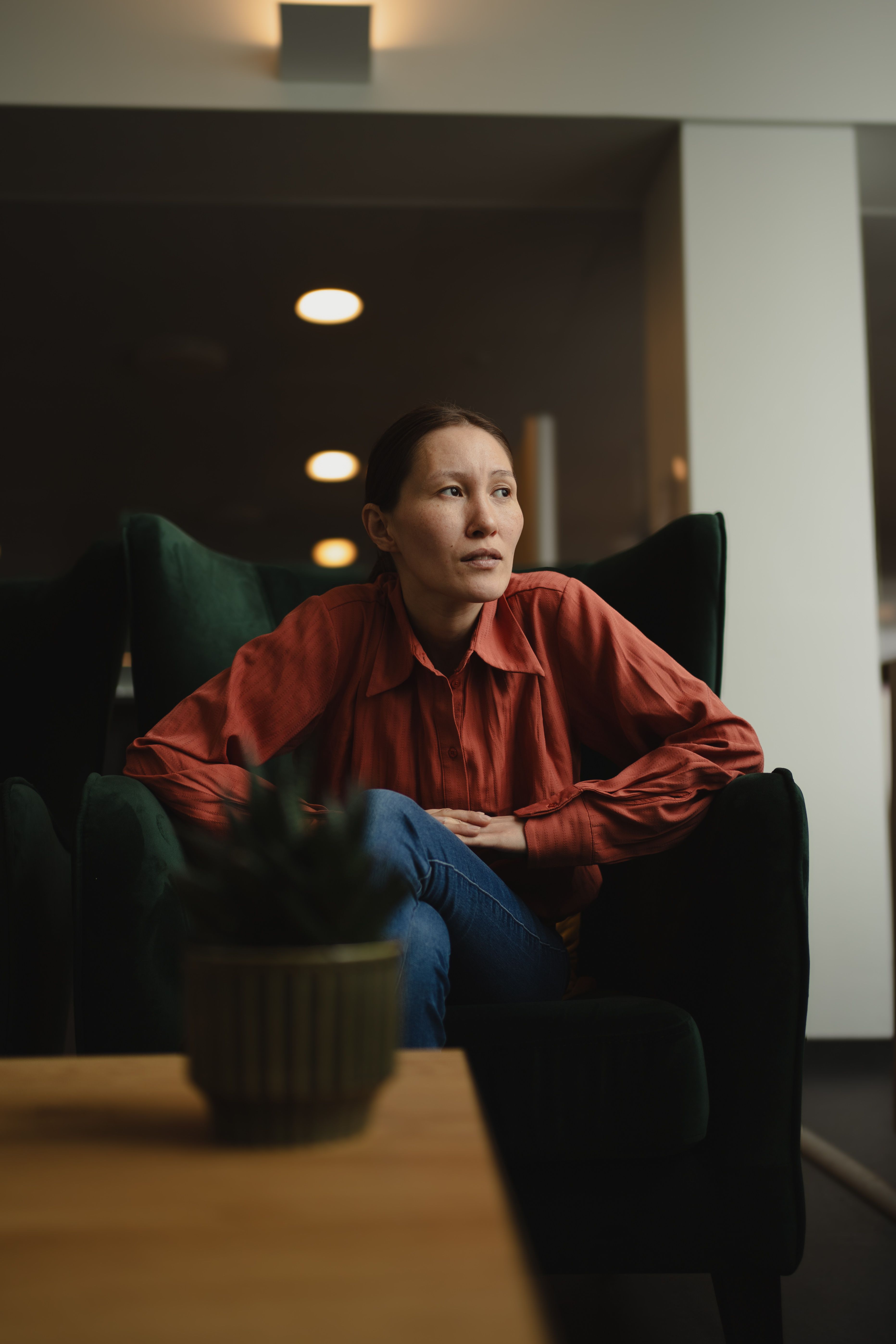 A reflective indoor portrait of an adult in Nuuk, Greenland, capturing a pensive mood.