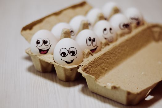Carton of eggs with funny smiley faces drawn, providing a whimsical touch to food photography.