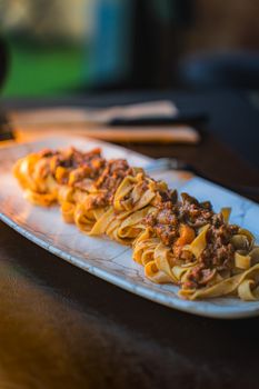 Delicious pappardelle pasta topped with rich, savory ragout on an elegant platter.