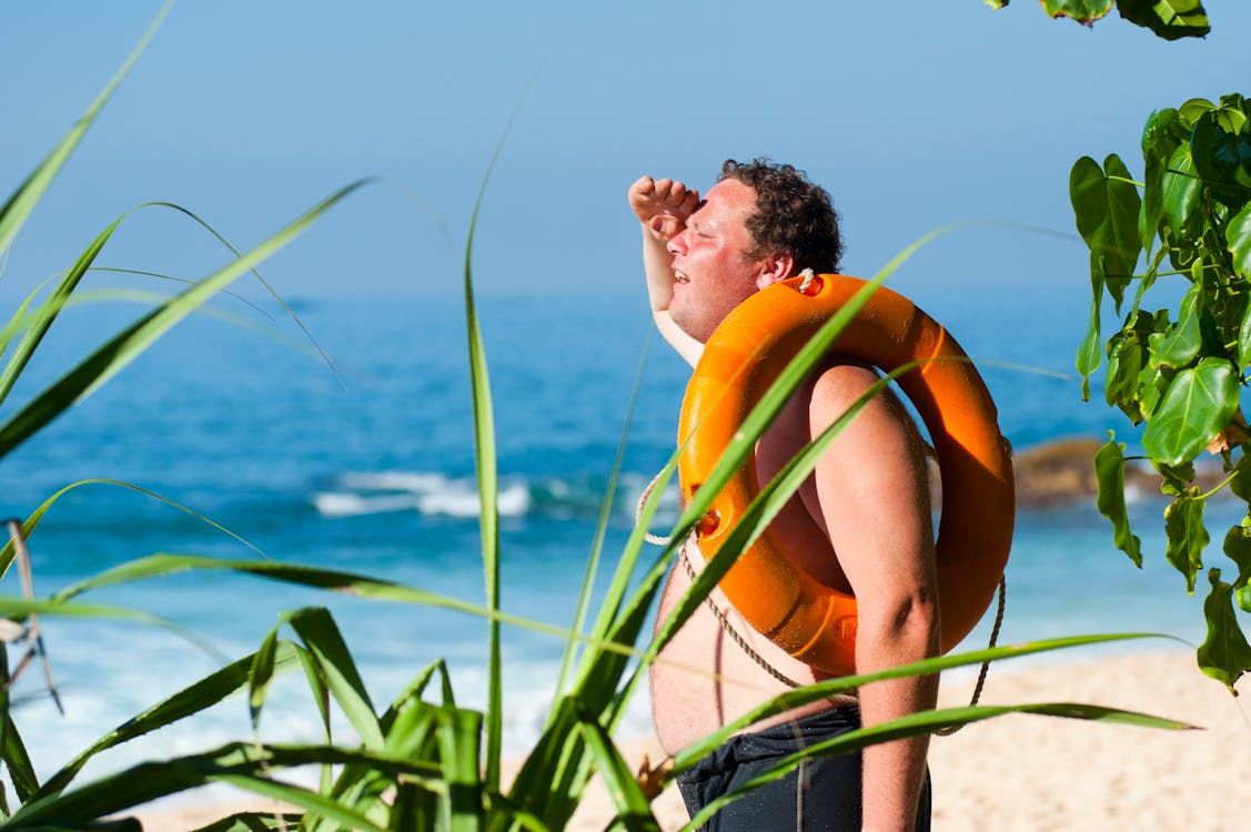 수역 근처의 남자 어깨에 주황색 안전 고리 · 무료 스톡 사진
