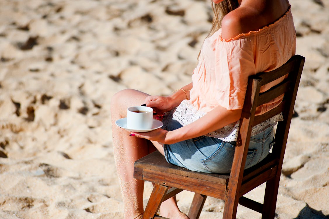 бесплатная Женщина, сидящая на стуле, держа чашку Стоковое фото