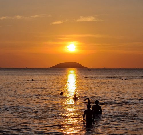 Free Beautiful sunset over the ocean in Nha Trang, Vietnam with silhouetted swimmers enjoying the view. Stock Photo