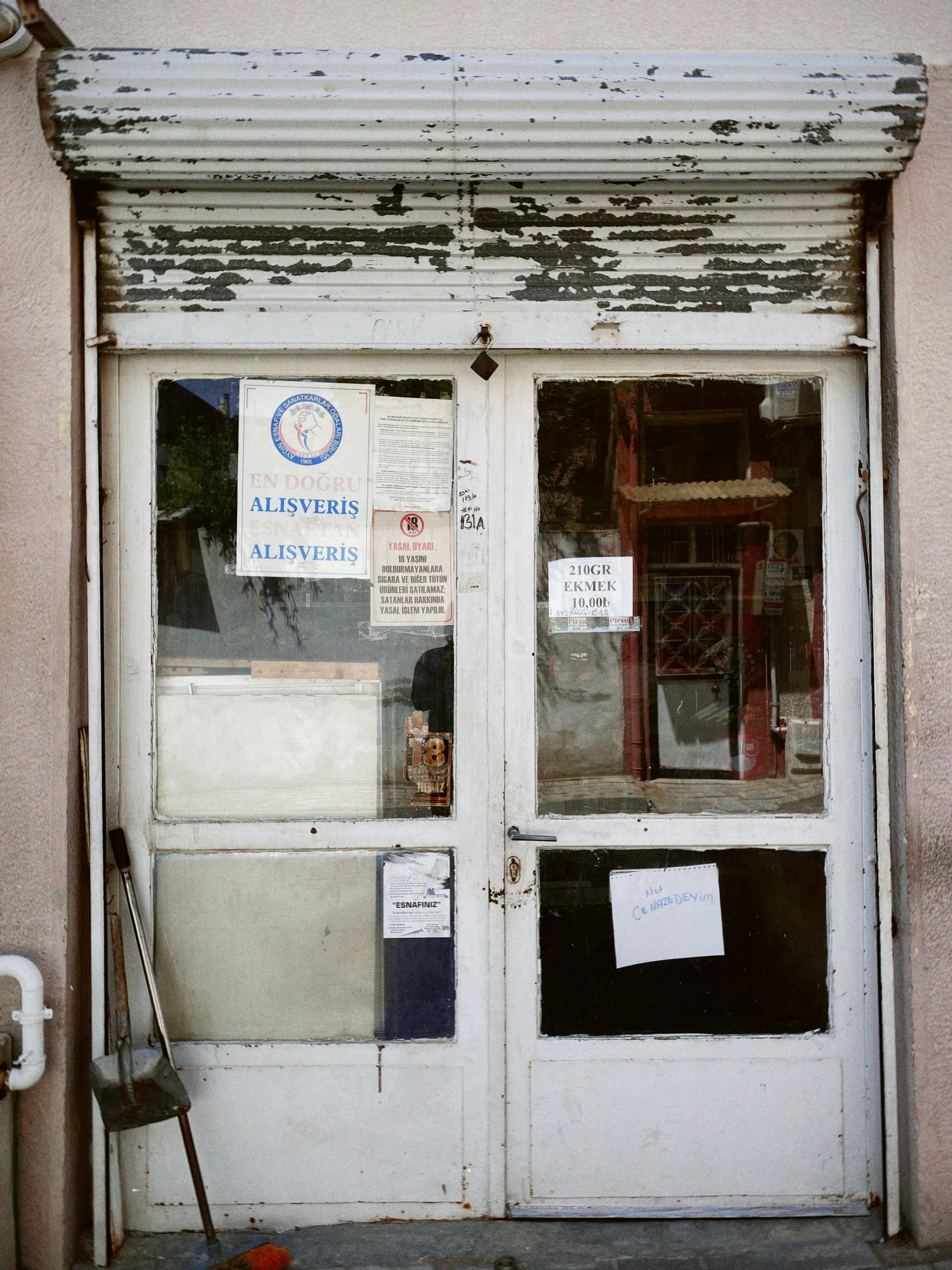 A weathered shopfront in Turkey with multiple signs and a closed notice on the door.