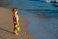 一个穿着泳衣的小女孩在海边玩耍，在阳光明媚的夏日里享受海滩