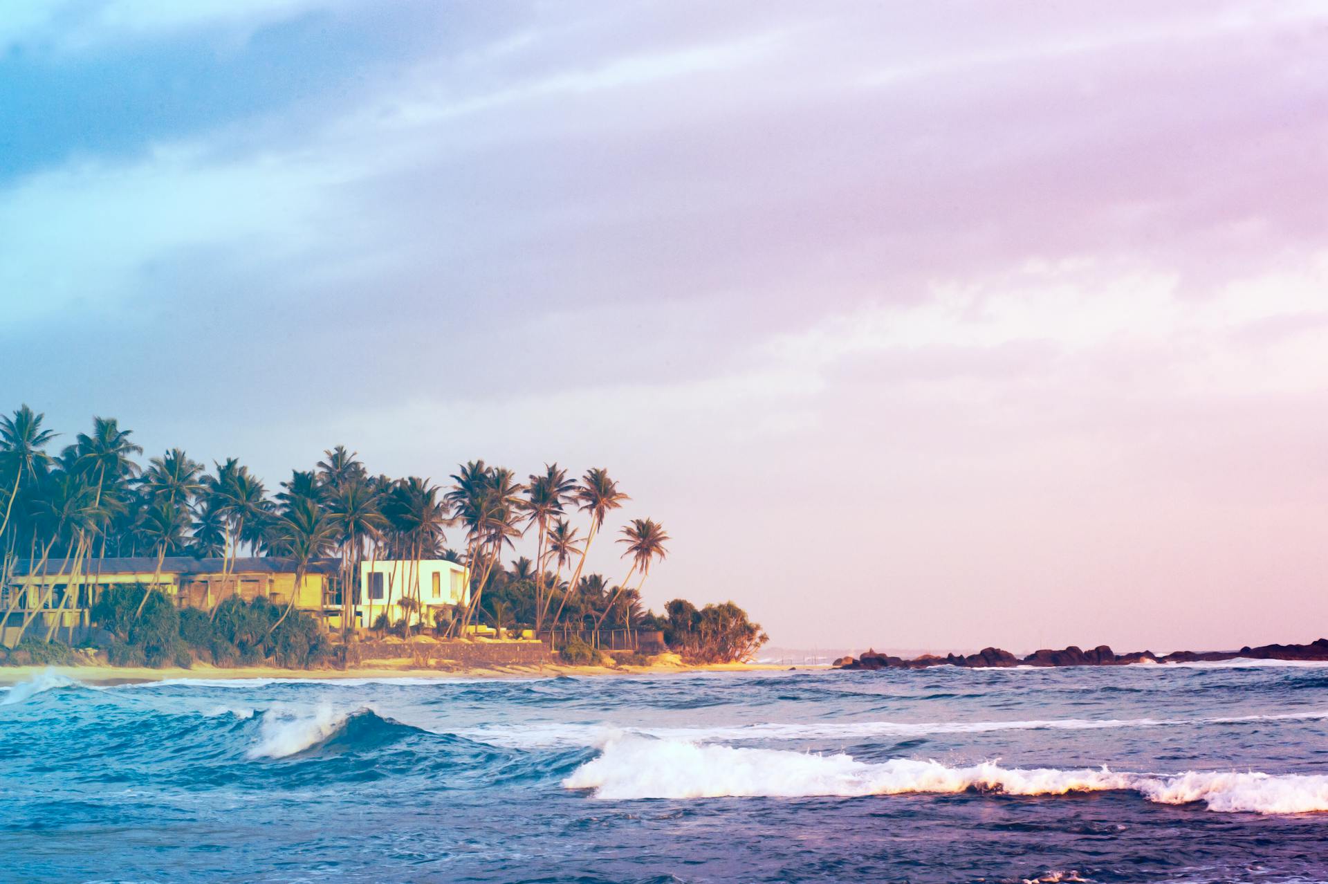 Serene beach with palm trees and waves in Dambulla, Sri Lanka at sunset.