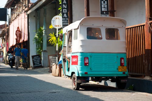 White and Teal Auto Rickshaw Beside Brown Wooden Rails