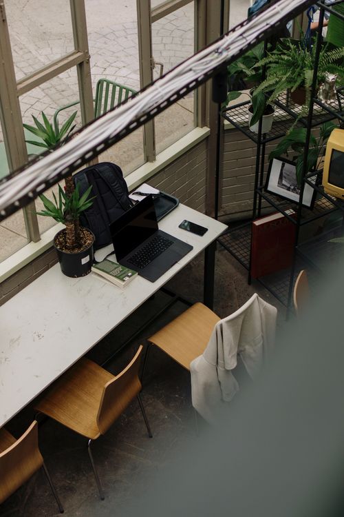 Free An inviting workspace with a laptop, chair, and greenery creating a refreshing ambiance. Stock Photo