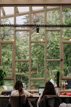 Office interior with large windows overlooking a lush green garden, providing a calm work environment.