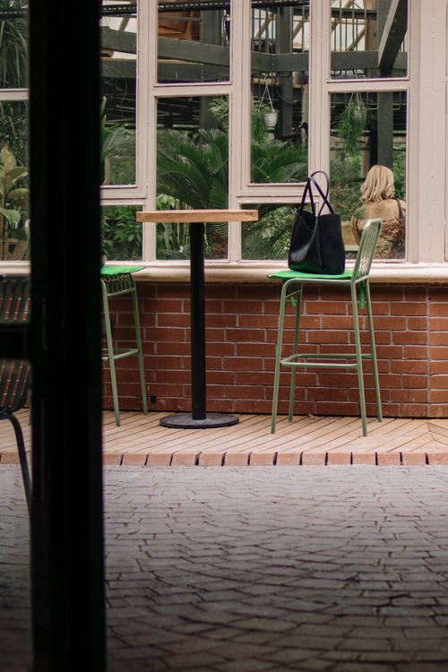 Free Empty chairs and table in a café setting with a bag, reflecting an inviting atmosphere. Stock Photo