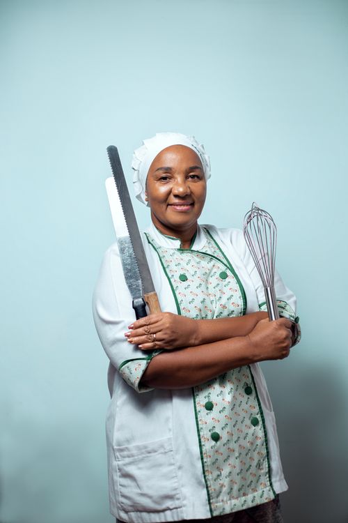 Free Smiling chef holding a knife and whisk, wearing uniform and cap. Stock Photo