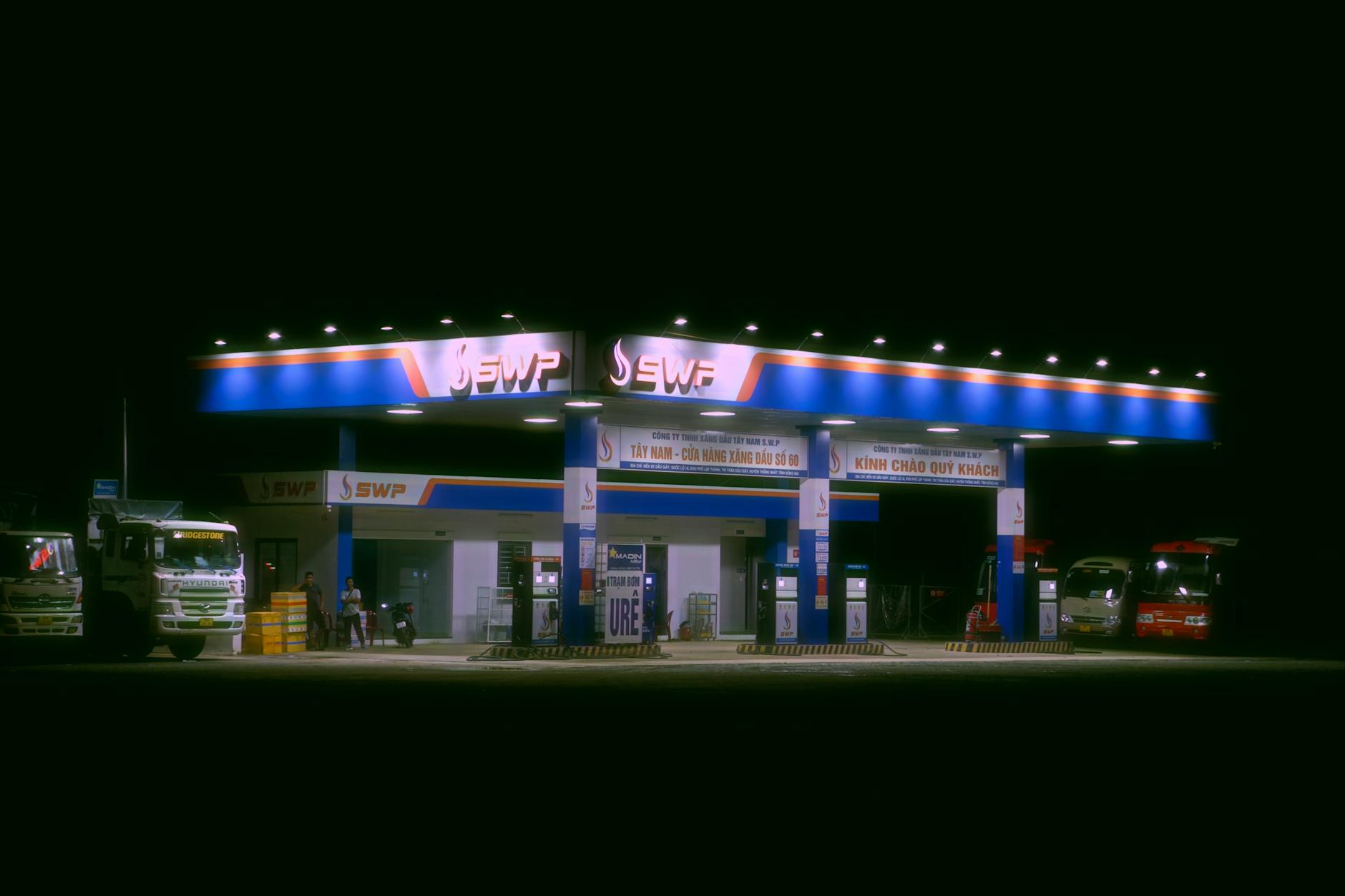 Nighttime view of a brightly lit gas station with trucks and cars parked.