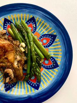 Vibrant meal featuring asparagus and chicken on a decorative plate. Bright and appetizing.