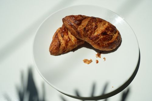 Free Golden croissants on a white plate with dramatic shadows in bright sunlight. Stock Photo