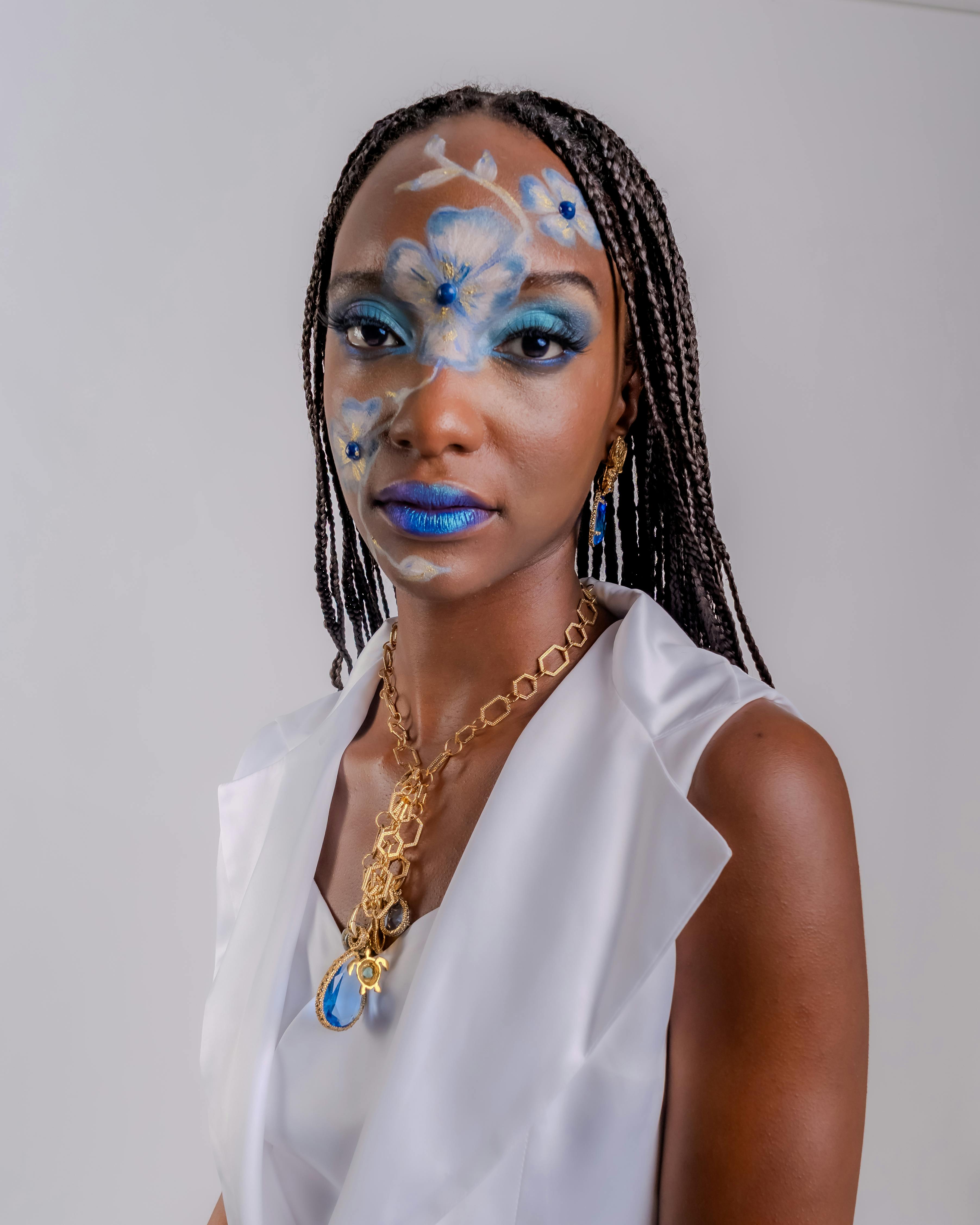 Portrait of a stylish woman with intricate blue floral makeup and jewelry, showcasing elegance and empowerment.