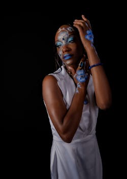 Elegant portrait of woman with creative blue floral makeup and white dress.