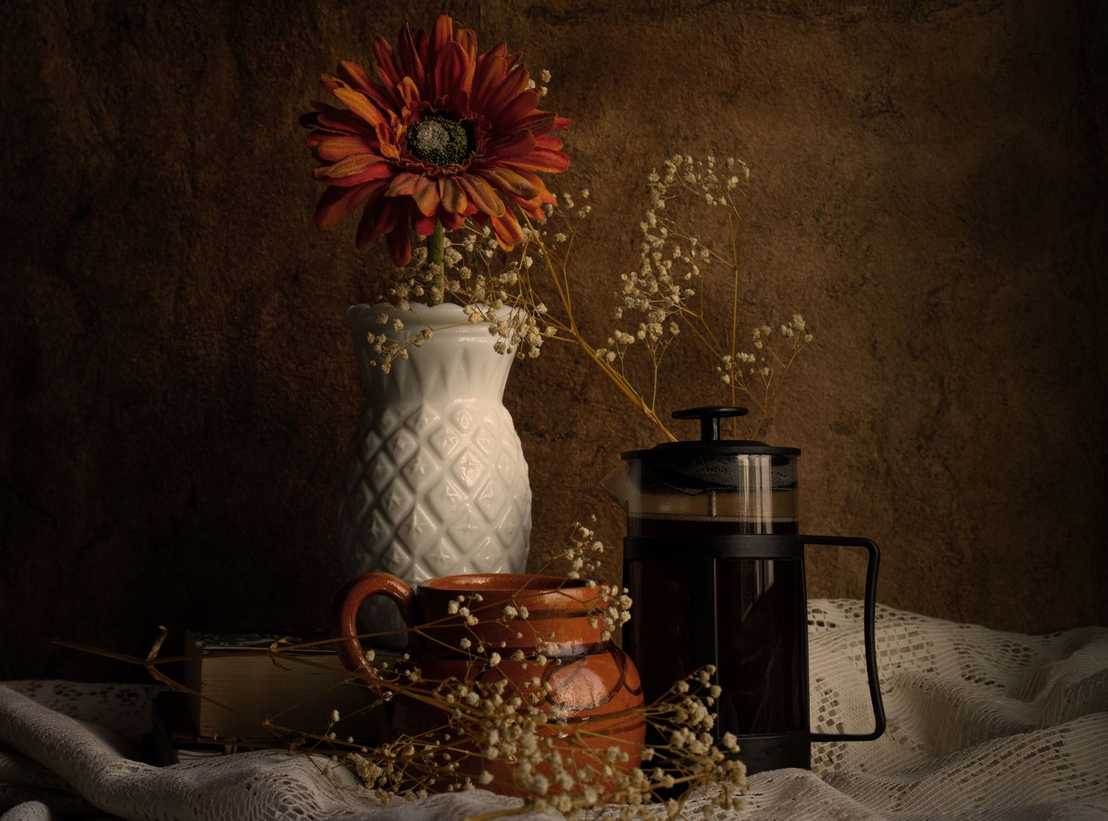 Low-lit still life of a flower vase, coffee press and pottery on a draped table — Alejandra Figueroa Ordoñez on Pexels