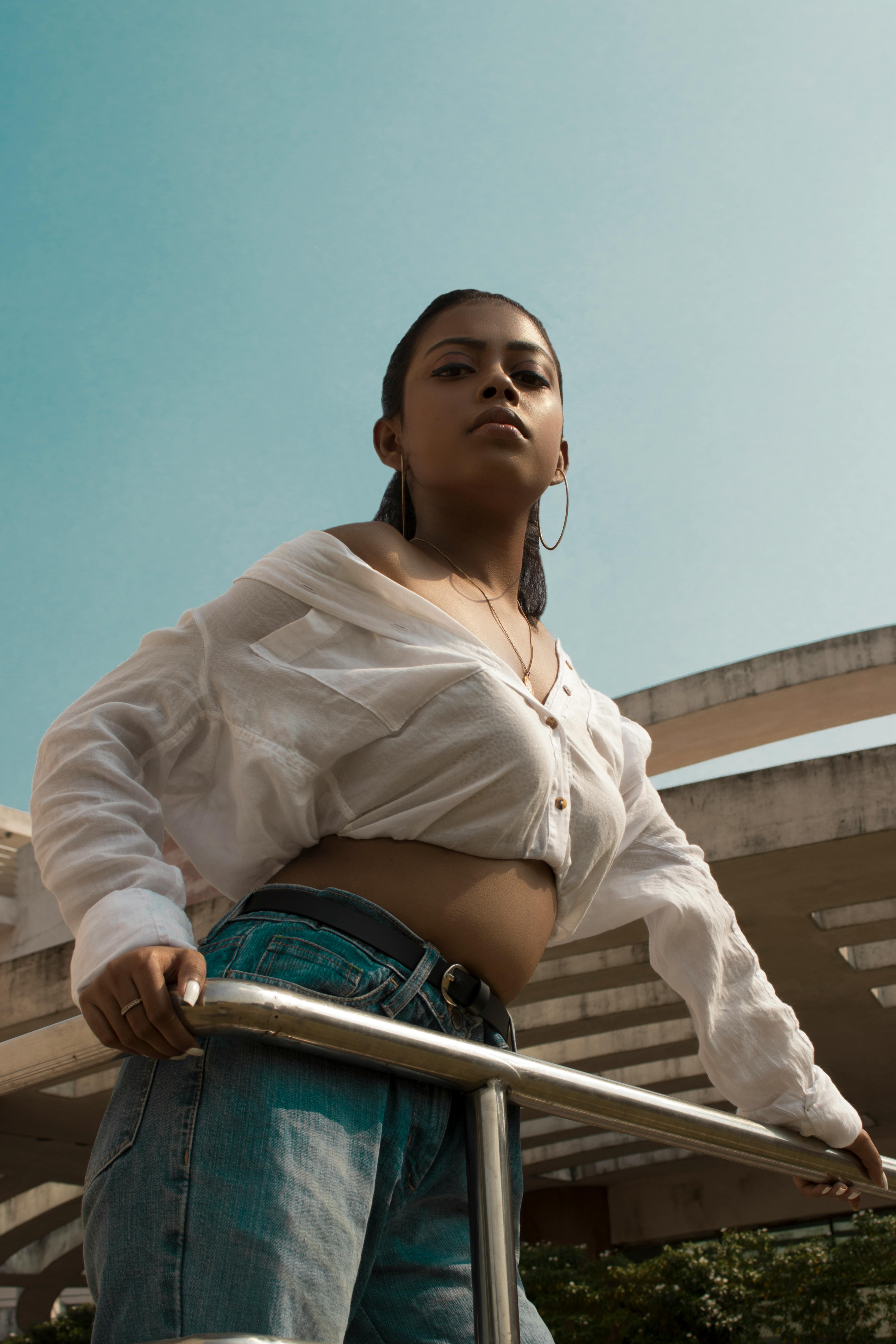 一位自信的年轻女性身着休闲时尚的服装，在现代建筑旁的户外合影