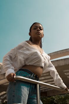 一位自信的年轻女性身着休闲时尚的服装，在现代建筑旁的户外合影