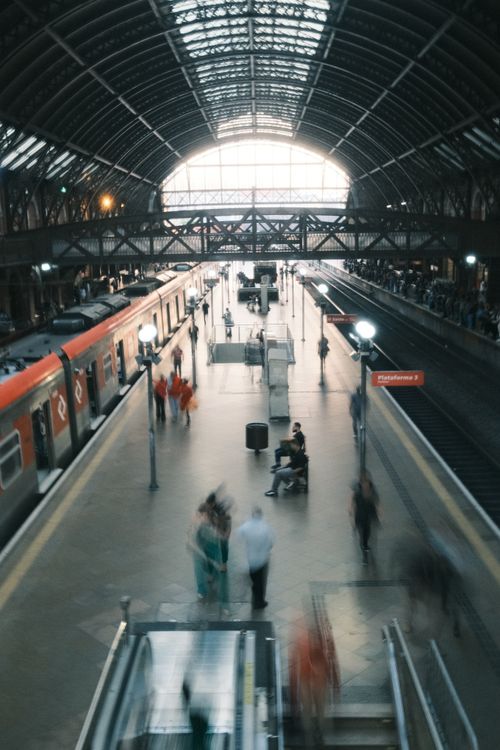 Free Busy scene inside a train station with commuters walking past platforms and trains. Stock Photo