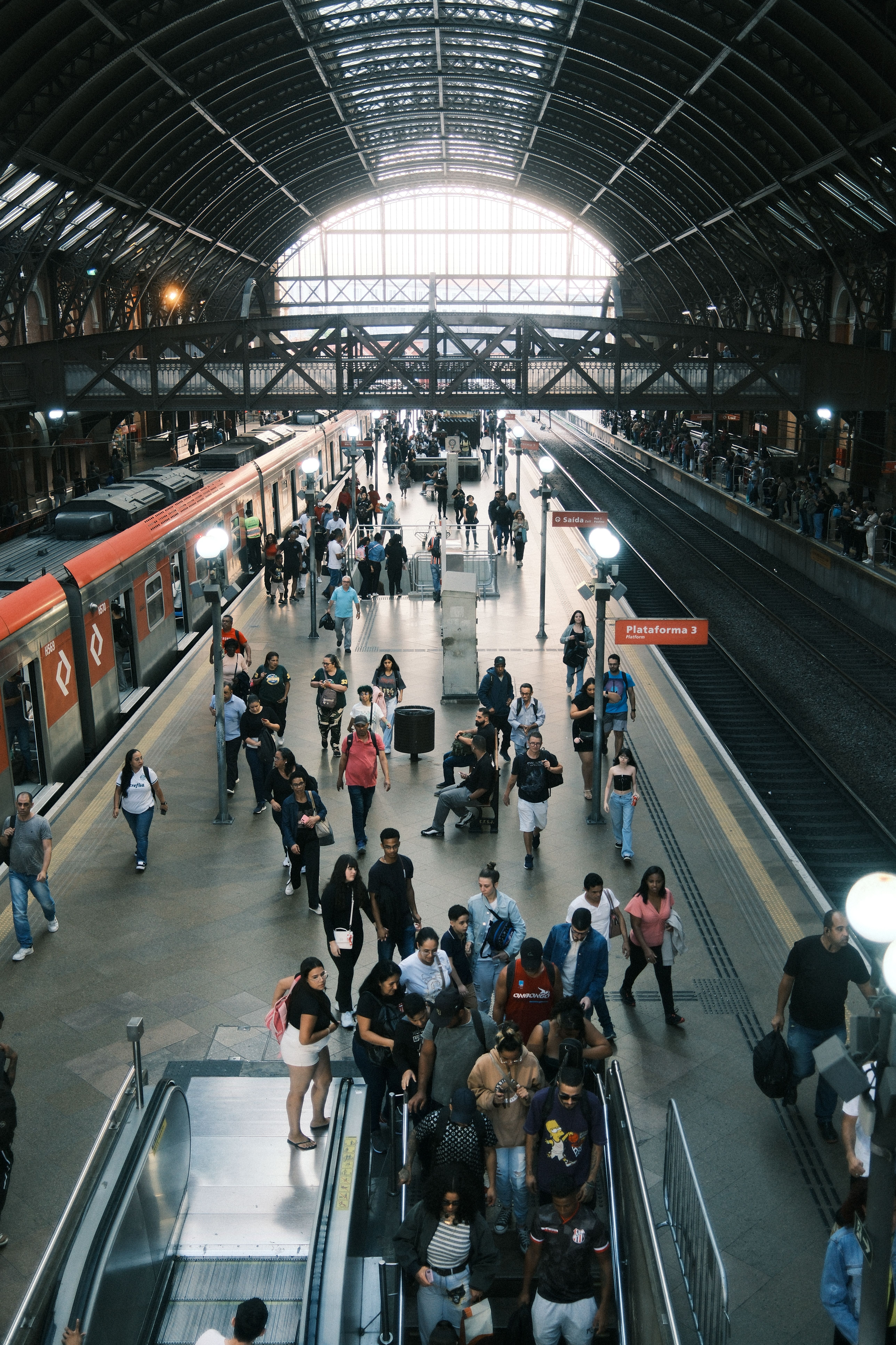 A busy train station with commuters moving through platforms and trains arriving.