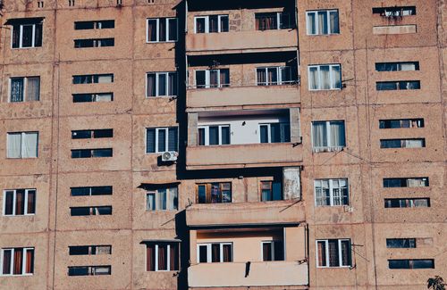 Free Close-up view of a mid-century urban apartment building facade with balconies and windows. Stock Photo
