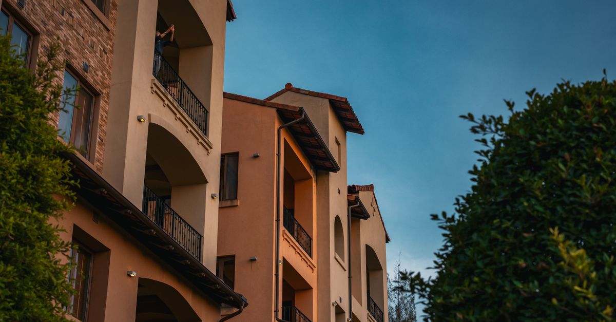 A stunning view of Italian-style architecture under the warm glow of a Thai sunset, framed by lush greenery.