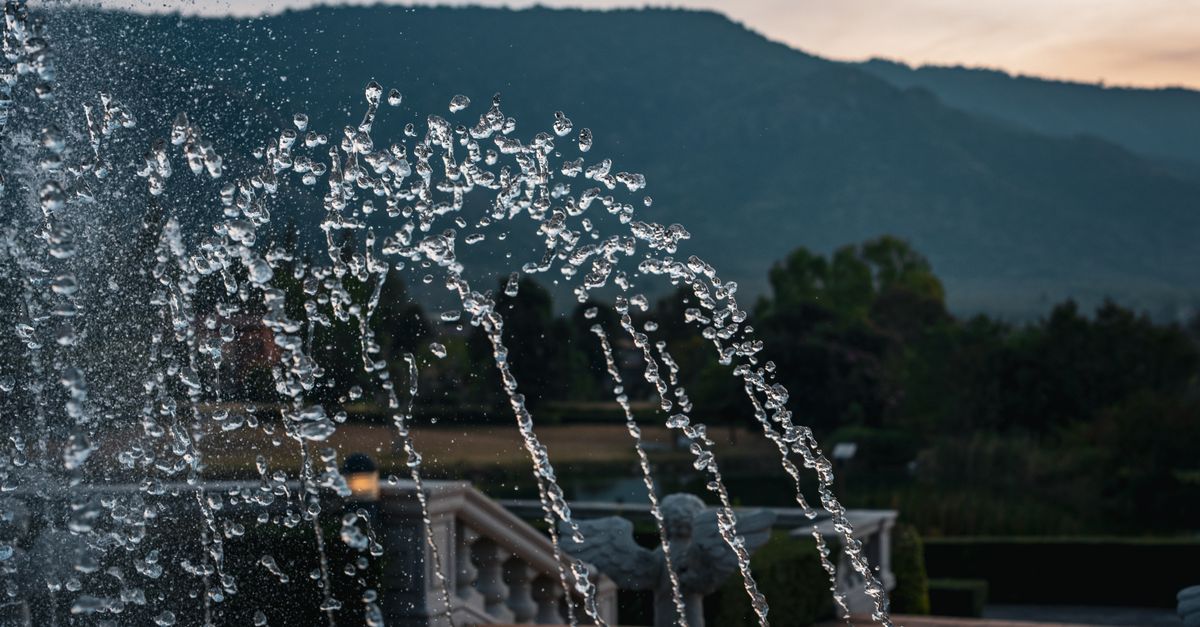 Captivating shot of a fountain with mountain backdrop at sunset in Thailand.