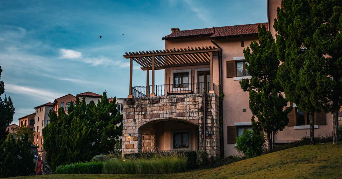 Charming rustic house with Tuscan-style architecture surrounded by lush greenery in Thailand's scenic outdoors.