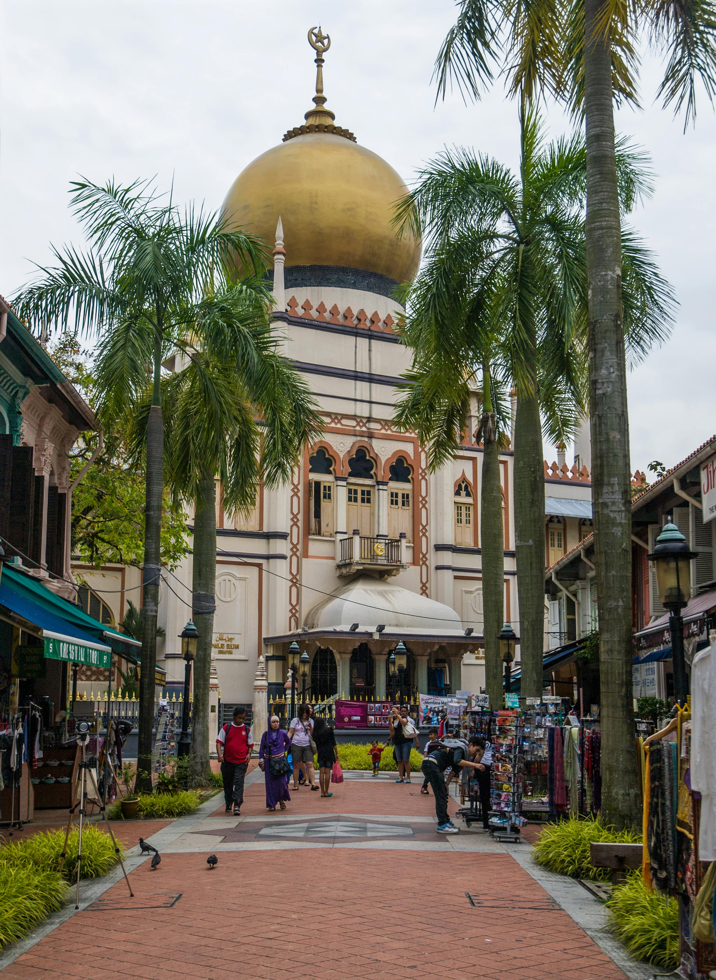 Bussorah Street lined with palm trees and restaurants leading to the golden-domed Sultan Mosque at dusk in Kampong Glam, Singapore