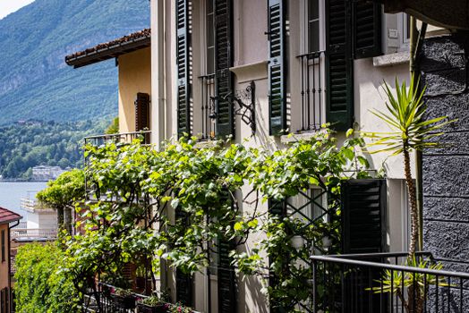Windows with shutters and greenery overlook Lake Como in Bellagio, Italy.
